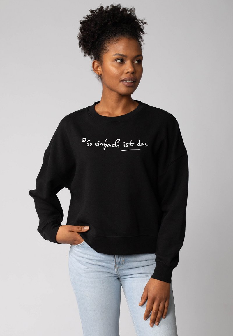 Schwarzer Pullover mit weißem Text "So einfach ist das" auf der Vorderseite, mit lässigem Schnitt und gerippten Bündchen und Saum.