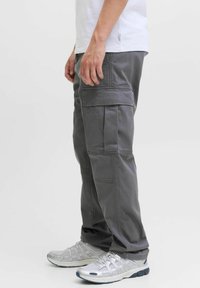 Grå cargobukser i bomull med flere lommer og en løs passform. Kombinert med lysegrå treningssko.