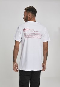 White t-shirt with red text on the back, featuring the word "skrrt" and an explanation of its meaning. Short sleeves, casual fit.