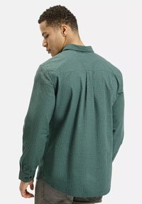 Zielona koszula w kratę z bawełny, z długimi rękawami, kołnierzykiem zapinanym na guziki oraz plisą z tyłu, zapewniającą luźny krój.