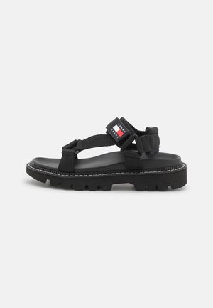 Sort sandal med chunky sål, justerbare stofstropper og et lille rektangulært Tommy Jeans-logo på anklen.