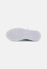 Witte rubberen sneakerzool met gestructureerde grippatronen, voorzien van een centraal logo en een gebogen hielvorm. Schoon, minimalistisch ontwerp.
