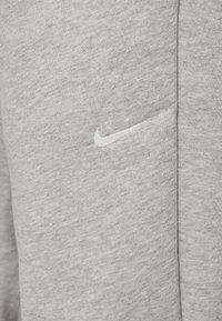 Grå bomulds sweatshirt med en tekstureret overflade, der har et subtilt hvidt Nike-logo syet foran.