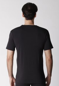 Maglietta nera a maniche corte, con scollatura a girocollo e un tessuto morbido e leggero. La vista posteriore mostra un design semplice e lineare.