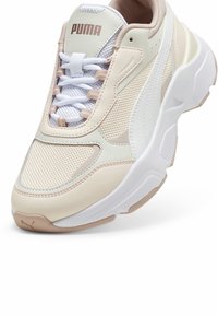 Baskets Puma avec dessus en mesh beige et blanc et cuir, forme arrondie, semelle en caoutchouc, et lacets blancs.