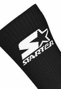 Calza nera a coste con una grande "S" bianca e un logo a stella sopra la parola "Starter" lavorata vicino alla parte superiore del risvolto.