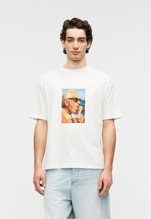 Weißes Baumwoll-T-Shirt mit einem bunten Grafikdruck eines Mannes mit Sonnenbrille, der Eiscreme isst, und dem Schriftzug "ease" in fetten weißen Buchstaben.