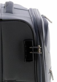 Maleta gris con un exterior liso y estructurado. Cuenta con cremalleras dobles y un asa moldeada y rígida para facilitar su transporte. Se observa un cierre lateral.