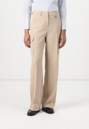 Beige Hose mit geradem Schnitt, ausgestattet mit zwei seitlichen Cargo-Taschen, glattem Stoff und einem schlanken Bund mit einem kleinen Metallelement.
