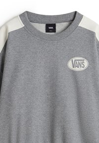 Gray sweatshirt with pale gray raglan sleeves, ribbed collar, and central logo patch. Soft texture, casual design, and small size label.