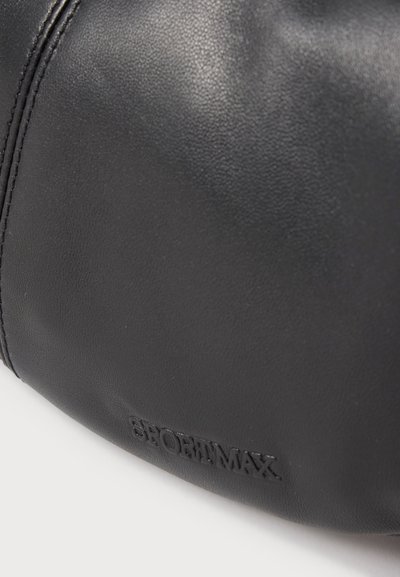 Gros plan d'une surface en cuir noir lisse avec le logo SPORTMAX embossé et des coutures visibles le long du bord.