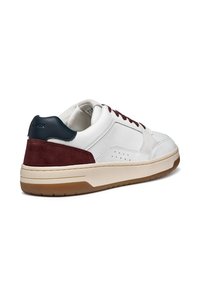 Zapatilla blanca de cuero con acentos de ante burdeos y talón azul marino. Presenta una suela de goma marrón y detalles perforados para transpirabilidad.