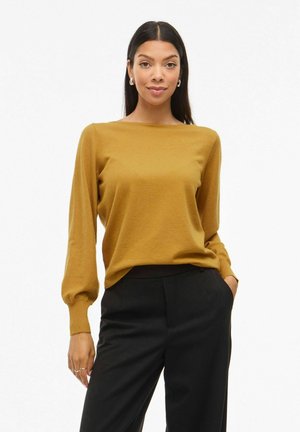 Mustard yellow knit sweater with long, puffed sleeves, round neckline, and a relaxed fit. Paired with black tailored trousers.