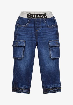 Jeans de carga infantiles de color azul oscuro con grandes bolsillos laterales, cinturilla elástica gris con la etiqueta "GUESS" y puños elásticos en los tobillos.
