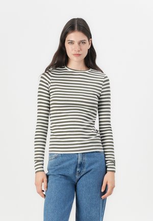 Langermet tettsittende topp med alternerende olivengrønne og hvite striper, ribbet tekstur og rund hals, kombinert med blå denimjeans.