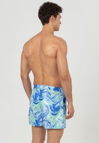 Zwemshorts met een blauw en groen gemarmerd patroon, een elastische tailleband en een ontspannen pasvorm. Het materiaal lijkt lichtgewicht en geschikt voor water.
