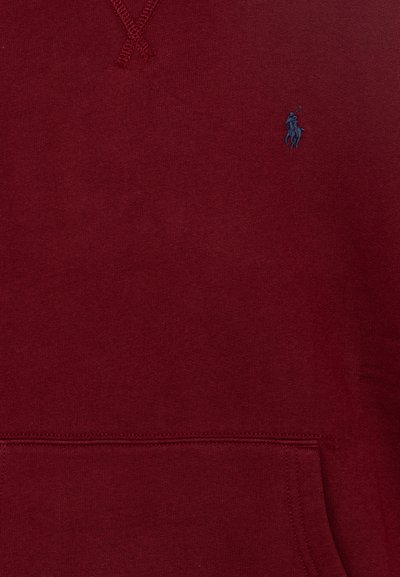 Sudadera marrón de tela suave con un bolsillo canguro, que presenta un pequeño logo azul marino en el pecho y un cordón texturizado en la capucha.