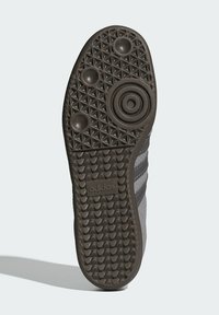 Svart gummisul med strukturerat grepp, med koncentriska cirkulära mönster och diamantformer. "adidas"-logotyp synlig i mitten.
