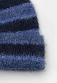 Cappello a maglia in righe blu scuro e blu. Il materiale sembra morbido con una texture soffice. Il risvolto è a coste, con sfumature diverse di blu.