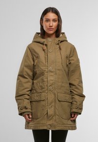 Giacca parka color khaki con cappuccio, ampie tasche frontali, chiusura con bottoni e dettagli con coulisse. Il tessuto appare robusto, con un design casual.