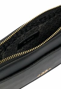 Black leather bag interior with a gold zipper. Lined with a black patterned fabric. Features a small brand label visible inside.