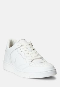 Vita läder låg sneaker med perforerad tå, snören och subtil logotyp på sidan, visad i en svagt vinklad position på en enkel bakgrund.