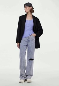 Fekete blézer, levendula színű top, világoskék, szakadt farmerekkel és fehér tornacipővel. Hátrafelé viselt sapka. Egyszerű dizájn, laza fazon.