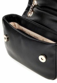 Borsa a mano in pelle nera con una texture liscia, hardware colore oro e un interno beige con il logo del marchio e frecce.