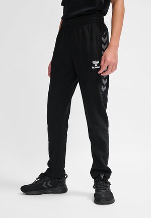 Zwarte joggerbroek met een elastische tailleband, voorzien van chevron-strepen aan de zijkanten en een Hummel-logo in het wit op de linker dij.