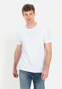 Hvid bomulds T-shirt med rund hals og korte ærmer, parret med blå denim jeans. Simpelt design, ingen synlige mønstre eller accenter.