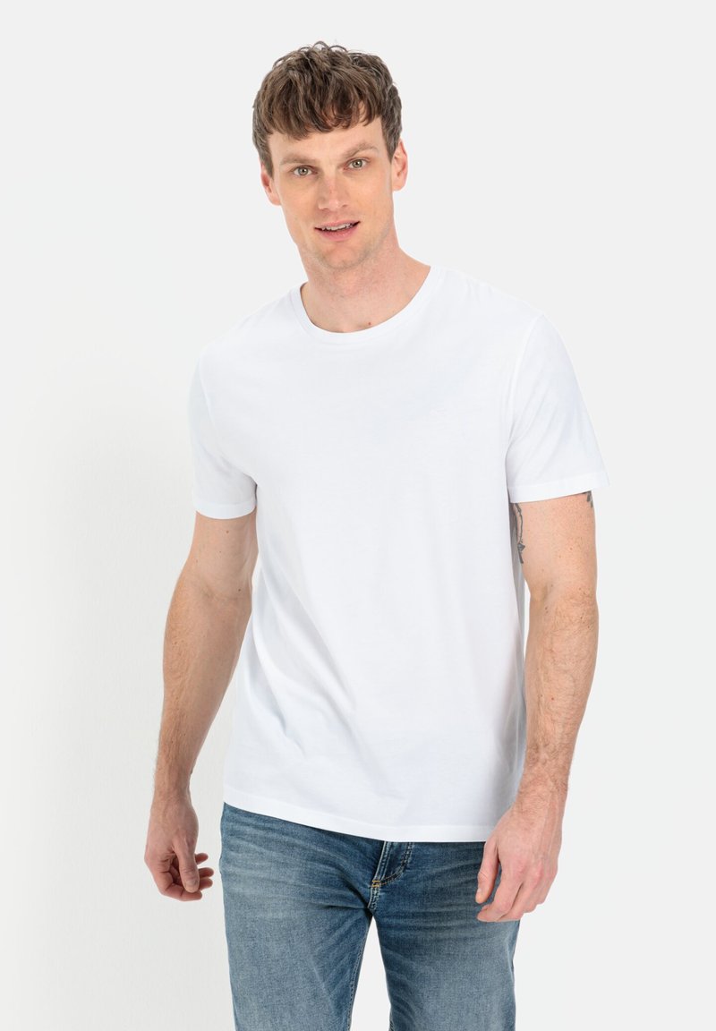 Hvid bomulds T-shirt med rund hals og korte ærmer, parret med blå denim jeans. Simpelt design, ingen synlige mønstre eller accenter.