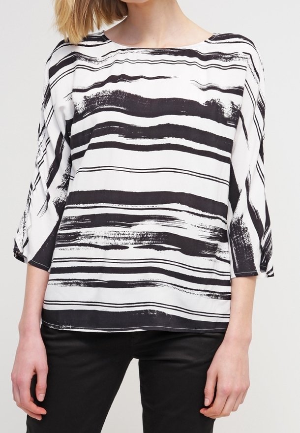 Blouse rayée noir et blanc avec un col rond, des manches trois-quarts et une coupe décontractée. Le tissu a une texture lisse.