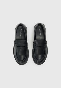 Černé kožené loafers s hladkým povrchem, zaoblenou špičkou a ozdobným páskem přes nárt. Gumová podrážka.