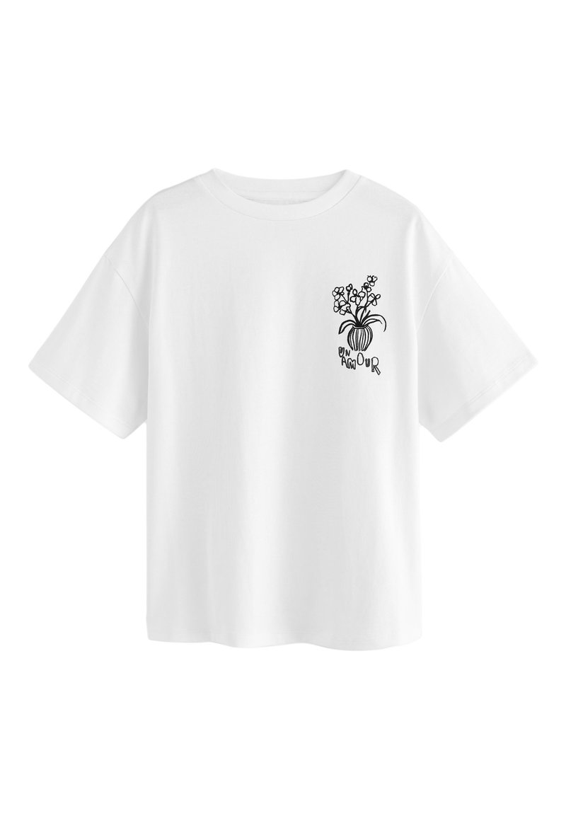 Camiseta blanca de algodón con un corte holgado, con un diseño floral negro y texto en el área del pecho izquierdo. Mangas cortas, cuello redondo.