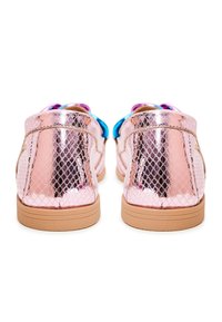 Chaussures plates rose métallique avec un motif peau de serpent et des semelles couleur sable, vues de dos sur fond blanc.