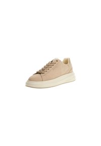 Sneaker beige a bassa cima con suola bianca spessa, lacci e il marchio "GUESS" sul lato e sull'etichetta dei lacci.