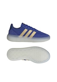 Modré sportovní boty s hladkým povrchem, které mají tři zlaté pruhy, zaoblenou špičku a průhlednou bílou podrážku.