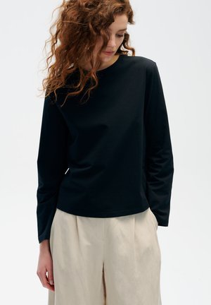 Czarna koszulka z długim rękawem i okrągłym dekoltem, wykonana z gładkiego materiału, charakteryzująca się luźnym krojem i minimalistycznym designem.