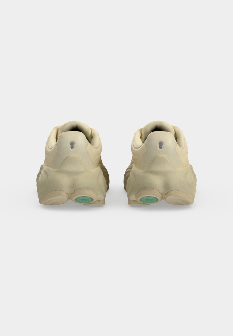 Coppia di sneakers beige vista da dietro con suole spesse e un piccolo dettaglio circolare sul fondo del tallone.