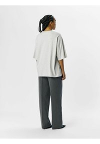 Lys grå oversized t-shirt med korte ærmer, parret med højtaljede grå bredbenede bukser. Glat stof med en løs pasform.