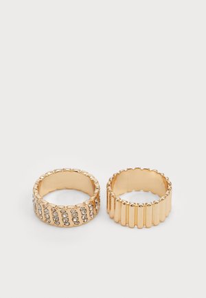 Goldene Ringe mit strukturiertem Design: einer mit vertikalen Rillen und der andere mit klaren Kristallen in horizontalen Reihen verziert.