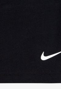 Čierne bavlnené tričko s malým bielym logom Nike. Tkanina je hladká s jemnou textúrou a klasickým strihom s okrúhlym výstrihom.