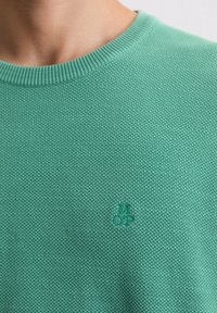 Maglione a maglia verde chiaro caratterizzato da una trama testurizzata, collo a girocollo a costine e un piccolo logo ricamato sul petto.