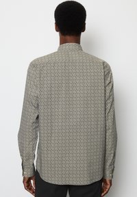 Lange mouw shirt in lichtgrijs met een klein zwart patroon. Heeft een staande kraag en knoopmanchetten. Goede textuur van de stof.