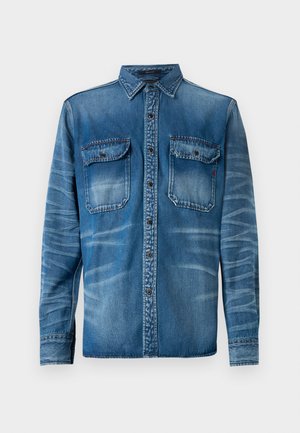 Jeanskjorte i middels blå med falmede områder. Har en spiss krage, frontknapplukking og to brystlommer med knappelokk.