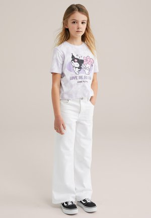 Hvide brede benjeans parret med en lavendelfarvet tie-dye t-shirt med tegneseriefigurer og teksten "ELSK MIG SOM JEG ER." Sorte sneakers.