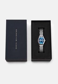 Silver stainless steel wristwatch with a blue dial, featuring Roman numerals, a silver mesh bracelet, nested in a dark blue box.