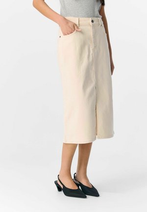 Beige denim midi-rok met een sluiting aan de voorkant met knopen, zijzakken en een rechte snit, gecombineerd met zwarte slingback hakken.
