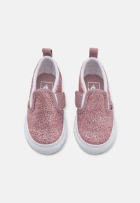Rozā slip-on kurpes ar mirdzošu spīdumu, baltām zole, un auduma augšdaļu. Iekļautas elastīgas sānu paneļi un cilpa vieglai uzvilkšanai.