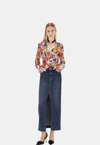 Blusa con stampa floreale e petali multicolori, gonna maxi in denim con spacco frontale e scarpe col tacco nere con dettagli in tessuto.